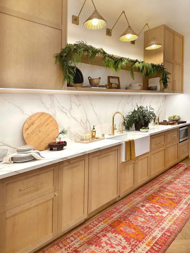 Warm residential kitchen with wood cabinetry and layered natural light.